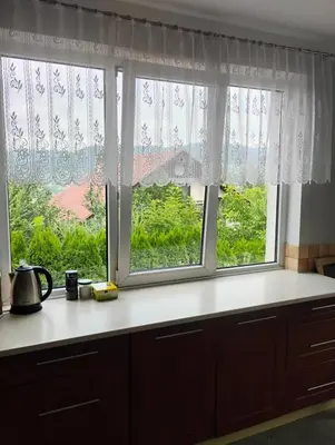a kitchen with two windows with curtains and a counter at Pokoje u Ewy in Limanowa