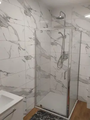 a shower with a glass door in a bathroom at Pokoje u Ewy in Limanowa