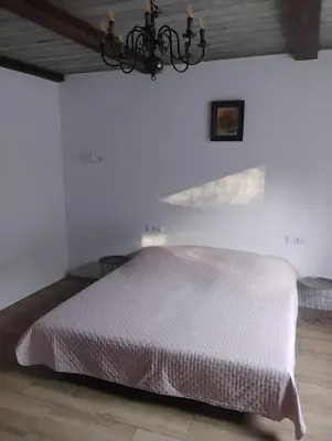 a white bedroom with a white bed with a chandelier at Pokoje u Ewy in Limanowa