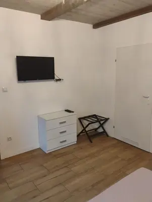 a white room with a dresser and a tv on a wall at Pokoje u Ewy in Limanowa