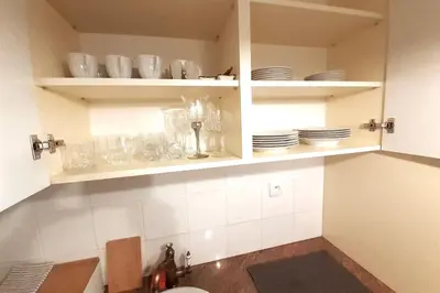 a kitchen with white cabinets with plates and dishes at Augustiańska Cozy Apartment A9 in Kraków