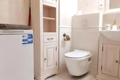 a white bathroom with a toilet and a sink at Augustiańska Cozy Apartment A9 in Kraków