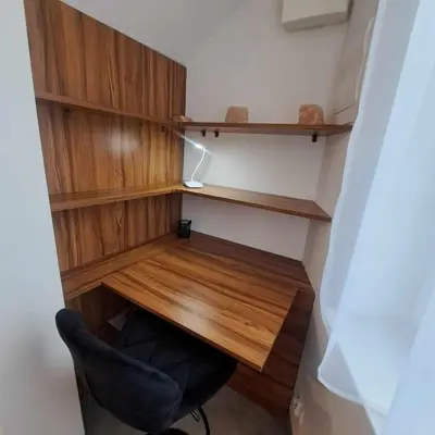 a desk and a chair in a room with wooden shelves at Apartament Gotowizna in Wadowice