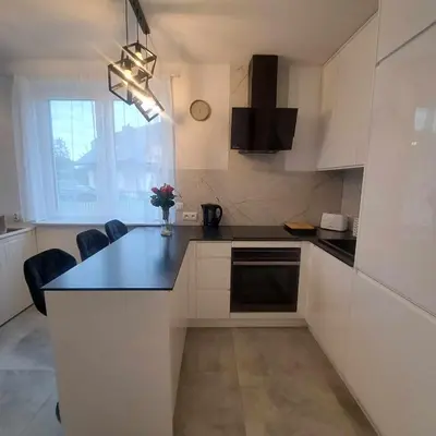a kitchen with white cabinets and a black counter top at Apartament Gotowizna in Wadowice