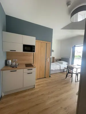 a room with a kitchen and a bedroom with a bed at Rent Apartment in Wieliczka