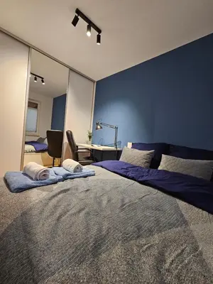 a bedroom with a large bed with a blue wall at Apartament Centralna Park in Kraków