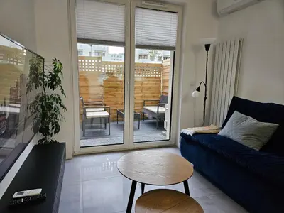 a kitchen with white cabinets and a wooden table at Apartament Centralna Park in Kraków