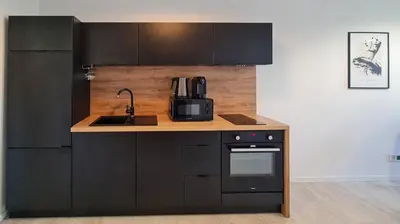 a kitchen with black cabinets and a microwave at Apartament Quiet Street 11, 6E in Oświęcim