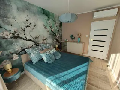 a bedroom with a bed with a floral wall at Apartament Miętowe Marzenie in Chrzanów