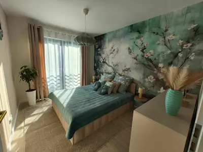 a bedroom with a bed with a floral wall at Apartament Miętowe Marzenie in Chrzanów