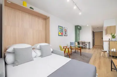 a bedroom with a white bed and a dining room at Ap with a balcony- Podgorze- Kalwaryjska 34 in Kraków