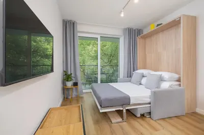 a bedroom with a bed and a couch and a window at Ap with a balcony- Podgorze- Kalwaryjska 34 in Kraków