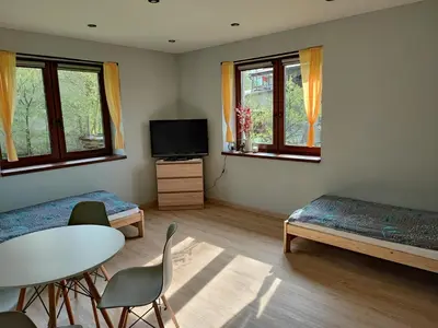 a room with a table and a bed and a tv at Apartamenty pod groniem in Sułkowice