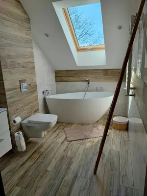 a bathroom with a white tub and a skylight at Apartamenty pod groniem in Sułkowice