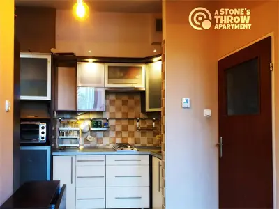 a kitchen with white cabinets and a sign on the wall at A Stone's Throw Apartment in Kraków