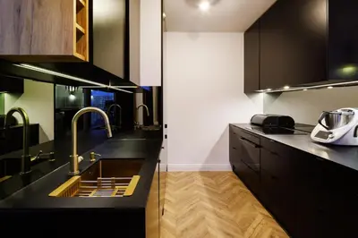 a kitchen with black counter tops and a sink at Mozarta sky terrace VIP 2-bed apartament in Kraków