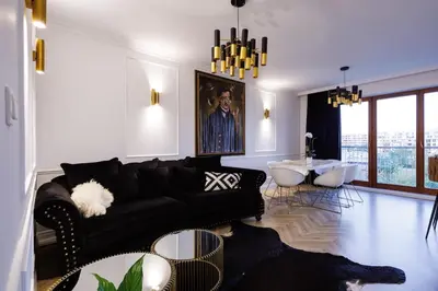 a living room with a black couch and a table at Mozarta sky terrace VIP 2-bed apartament in Kraków