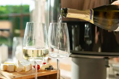 a bottle of wine being poured into two wine glasses at Leśna Przystań Gorce in Nowy Targ