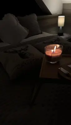 a candle on a table in front of a bed at Leśna Przystań Gorce in Nowy Targ
