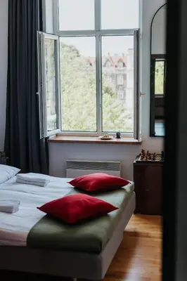 a bedroom with a bed with red pillows and a window at Margarita Panorama Old Town View in Kraków