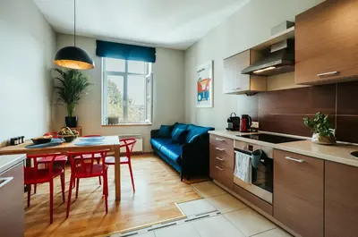 a kitchen and living room with a table and a blue couch at Margarita Panorama Old Town View in Kraków