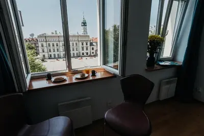a chair in front of a window with a view of a building at Margarita Panorama Old Town View in Kraków