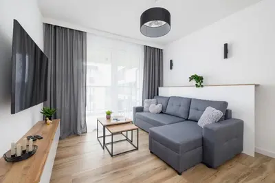 a living room with a couch and a table at Nowoczesny Apartament z Parkingiem na Alei Pokoju w Krakowie by Noclegi Renters in Kraków