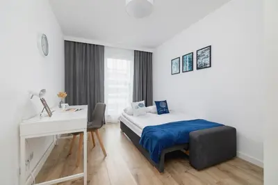 a white bedroom with a bed and a desk and a desk at Nowoczesny Apartament z Parkingiem na Alei Pokoju w Krakowie by Noclegi Renters in Kraków