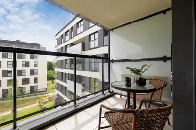 a balcony with a table and chairs and a large window at Nowoczesny Apartament z Parkingiem na Alei Pokoju w Krakowie by Noclegi Renters in Kraków