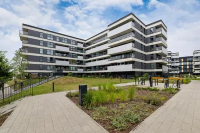 an apartment building with a park in front of it at Nowoczesny Apartament z Parkingiem na Alei Pokoju w Krakowie by Noclegi Renters in Kraków