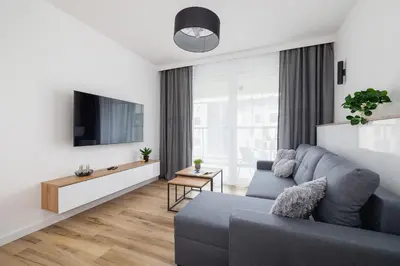 a living room with a blue couch and a tv at Nowoczesny Apartament z Parkingiem na Alei Pokoju w Krakowie by Noclegi Renters in Kraków