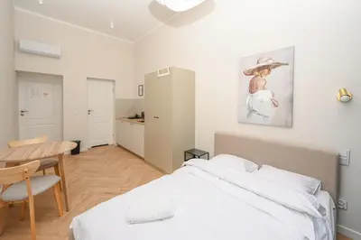 a white bedroom with a bed and a table at RentPlanet - Studio plac Matejki in Kraków
