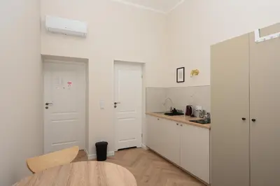 a kitchen with white cabinets and a wooden table at RentPlanet - Studio plac Matejki in Kraków