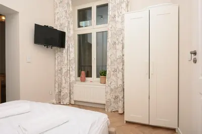 a white bedroom with a bed and a window at RentPlanet - Studio plac Matejki in Kraków