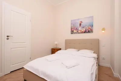 a bedroom with a white bed with a painting on the wall at RentPlanet - Studio plac Matejki in Kraków
