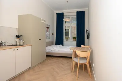 a small kitchen and a table in a room with a bed at RentPlanet - Studio plac Matejki in Kraków