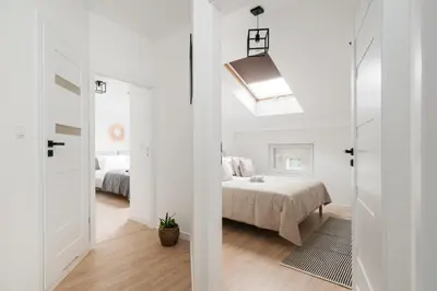 a white bedroom with a bed and a window at Dragonfly Old Town Apartment - bespoke apartments in Kraków