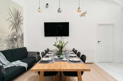 a living room with a table and a green couch at Dragonfly Old Town Apartment - bespoke apartments in Kraków