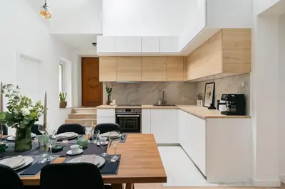 a kitchen with a dining table and a kitchen with white cabinets at Dragonfly Old Town Apartment - bespoke apartments in Kraków