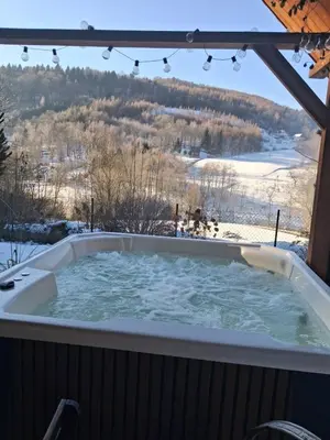 a jacuzzi tub with a view of a snowy mountain at Domek za lasem in Laskowa