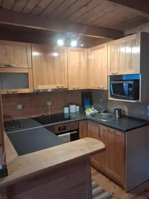 a kitchen with wooden cabinets and a counter top at Domek za lasem in Laskowa