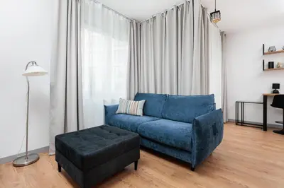 a living room with a blue couch and a ottoman at City of the Kings - Riverside B22 in Kraków