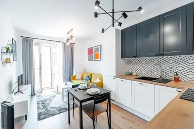 a kitchen with black cabinets and a table in a room at Kraków Bagry Apt - Parking, Balcony, Workspace - by Rentujemy in Kraków