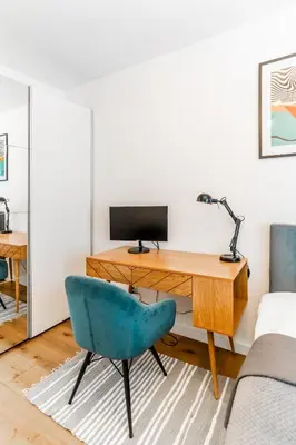 a desk with a computer and a blue chair in a room at Kraków Bagry Apt - Parking, Balcony, Workspace - by Rentujemy in Kraków