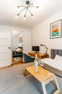 a bedroom with a bed and a table with wine glasses on it at Kraków Bagry Apt - Parking, Balcony, Workspace - by Rentujemy in Kraków