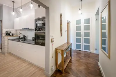 a kitchen with white cabinets and a wooden floor at Apartament Lubomirskiego Centrum Kraków in Kraków