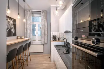 a kitchen with black and white appliances and bar stools at Apartament Lubomirskiego Centrum Kraków in Kraków