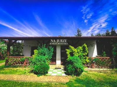 a house with a sign on the front of it at Agroturystyka na Jurze Apartamenty z widokiem na Zamek Jacuzzi Sauna Beczka in Ogrodzieniec