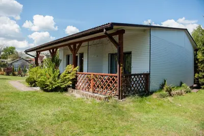 a small house with a porch on a lawn at Agroturystyka na Jurze Apartamenty z widokiem na Zamek Jacuzzi Sauna Beczka in Ogrodzieniec