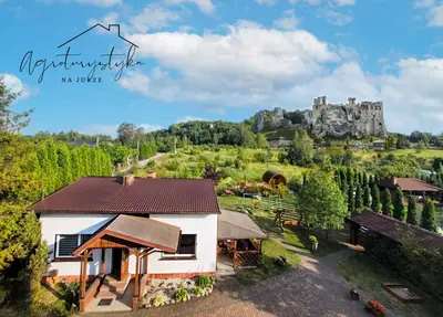 an aerial view of a house with a castle in the background at Agroturystyka na Jurze Apartamenty z widokiem na Zamek Jacuzzi Sauna Beczka in Ogrodzieniec